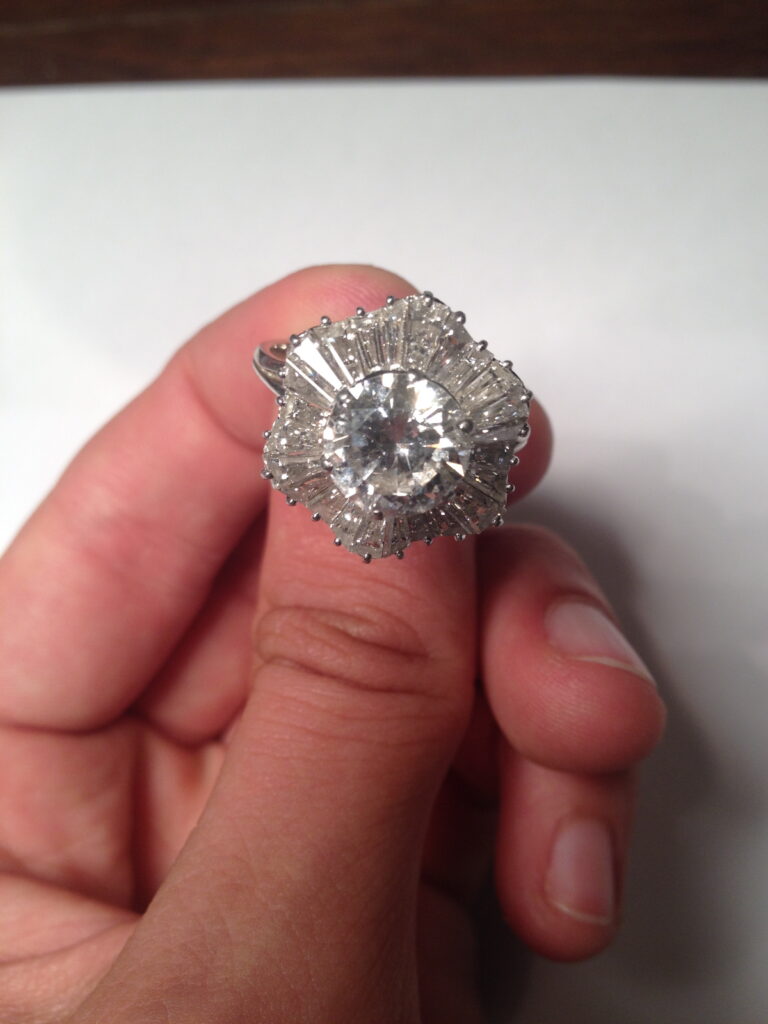 Bague en or gris 18 k et platine 950 millièmes. Elle est ornée d'un brillant d'environ 2,50 cts. Il est disposé dans un entourage juponné de diamants tapers. Tour de doigt: 59 (boules rétrécisseuses). Poids brut: 7 g..jpg
