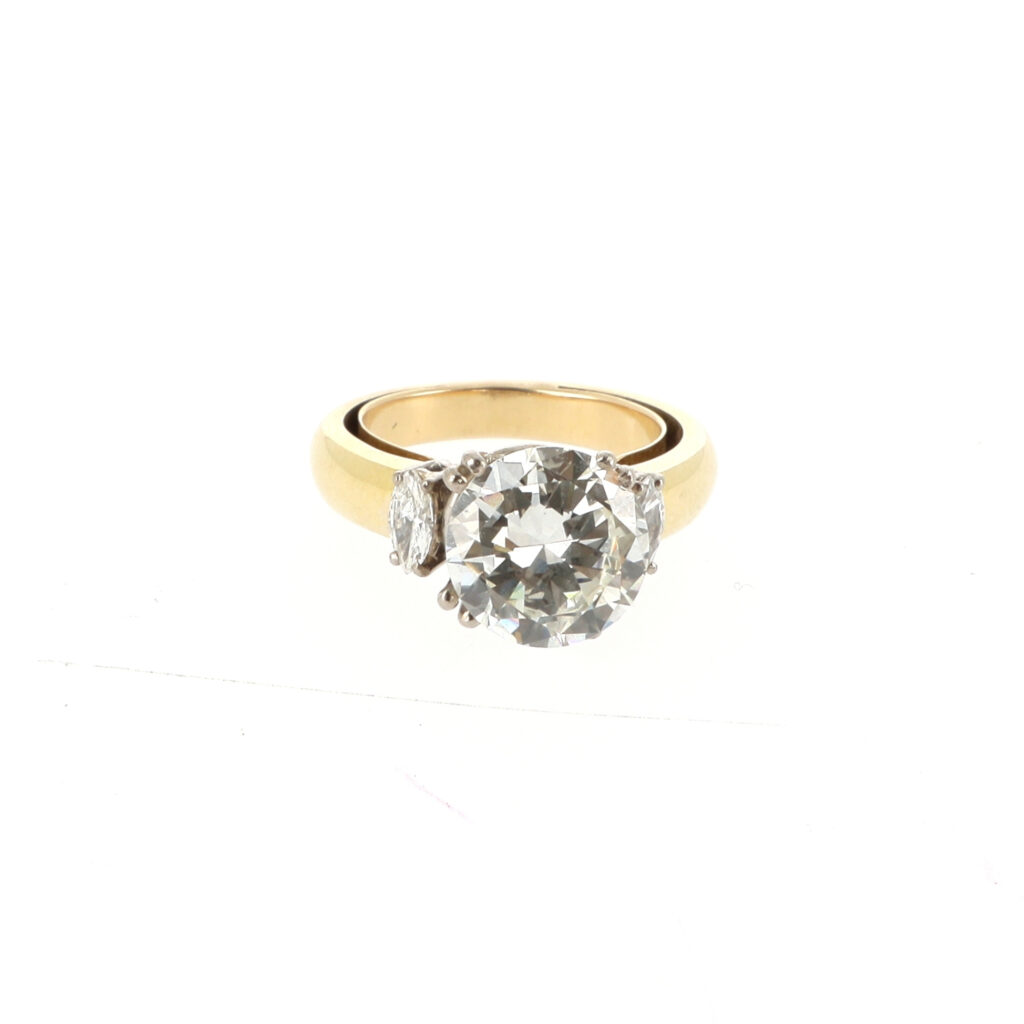 Solitaire en or gris et jaune 18k (750 millièmes) centrée d'un diamant taille brillant de 2.90 carats, de couleur I et pureté VS2, épaulé de deux diamants navettes. Dim. diamant : 9.67 - 9.75 x 5.14 mm Doigt 50_Adjugé 13 500