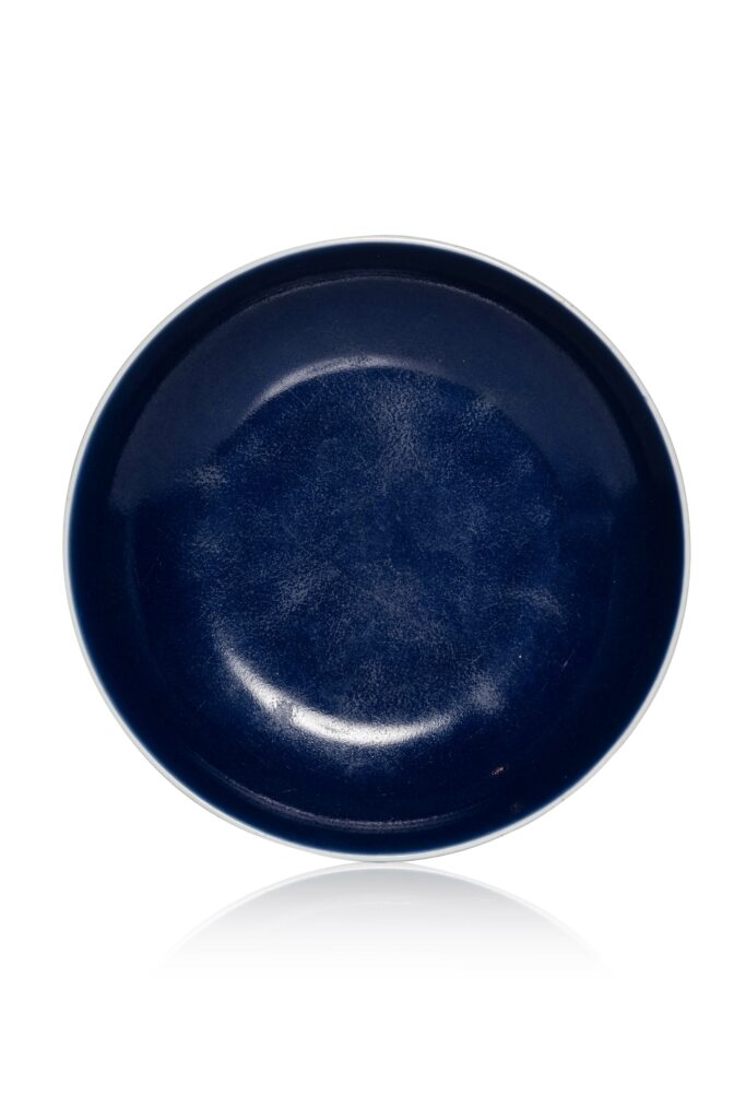 N4230-0011_CHINE, Marque et époque Qianlong, XVIIIe siècle, Coupelle en porcelaine,Montée sur un court pied, la paroi circulaire, revêtue sur l'ensemble d'une couverte monochrome bleu sacrificiel dit "ji lan". Une marque Qianlong à six caractères en bleu de cobalt sous la base. Hauteur : 4 cm Diamètre : 16 cm Adjugé 15 000 €