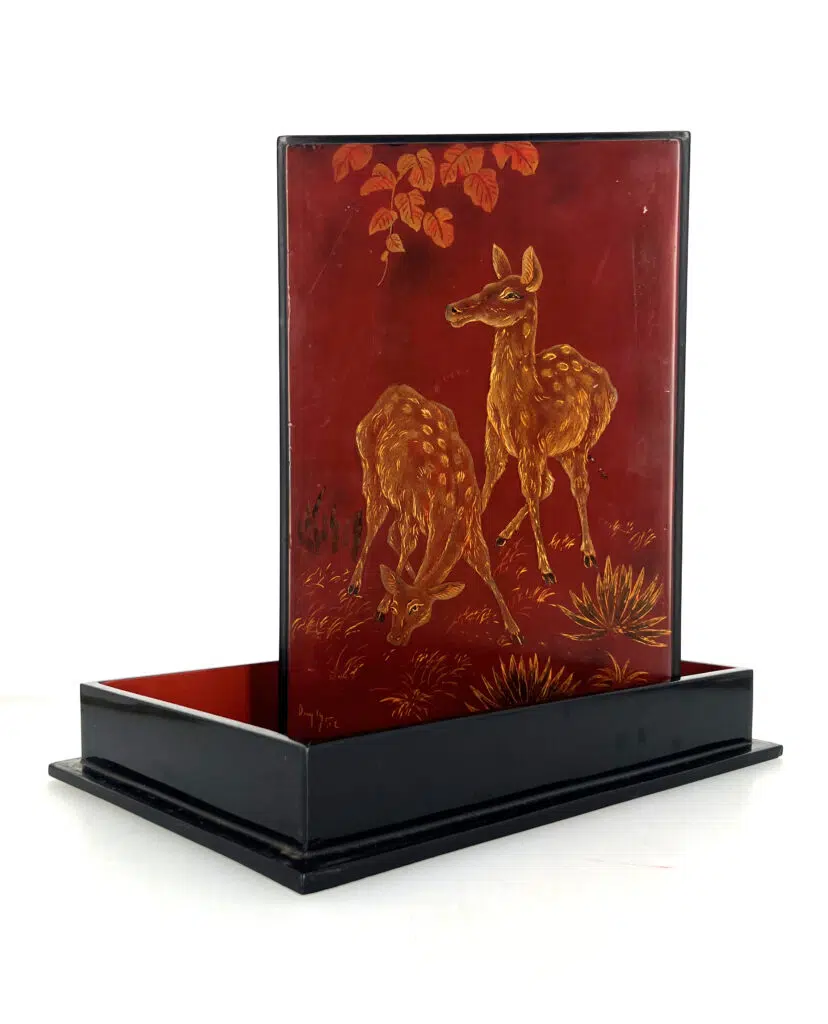 P2402-0002, de forme quadrangulaire, présentant sur le couvercle un décor en laque or et ocre sur fond rouge de deux biches dans la jungle. L’intérieur en laque rouge portant l’inscription «Tran-Phuc-Duyen, Artiste laqueur, Hanoï, Vietnam, 146 av. du Grand Bouddha». 30 x 20 cm