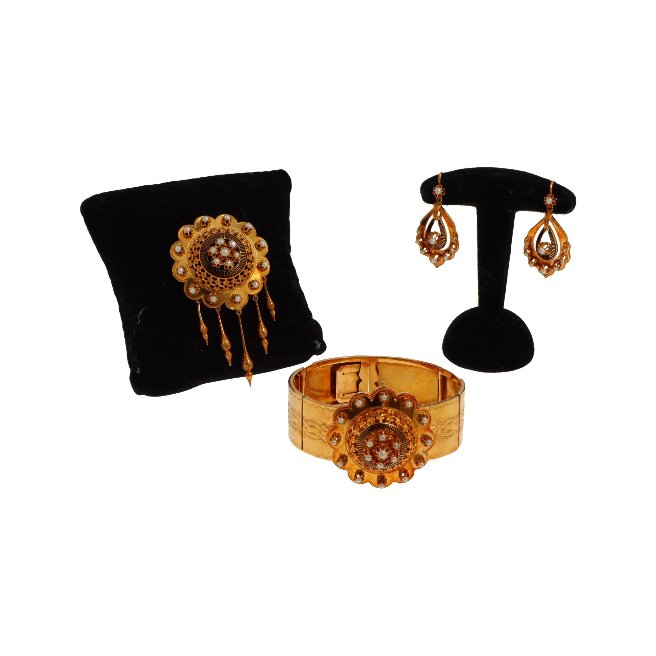Parure or et perles - Parure en or jaune 18k (750 millièmes) comprenant un bracelet, une broche et une paire de pendants d'oreilles, l'ensemble à décor ciselé souligné de demi perles* et d'émail noir. Le motif central du bracelet amovible.