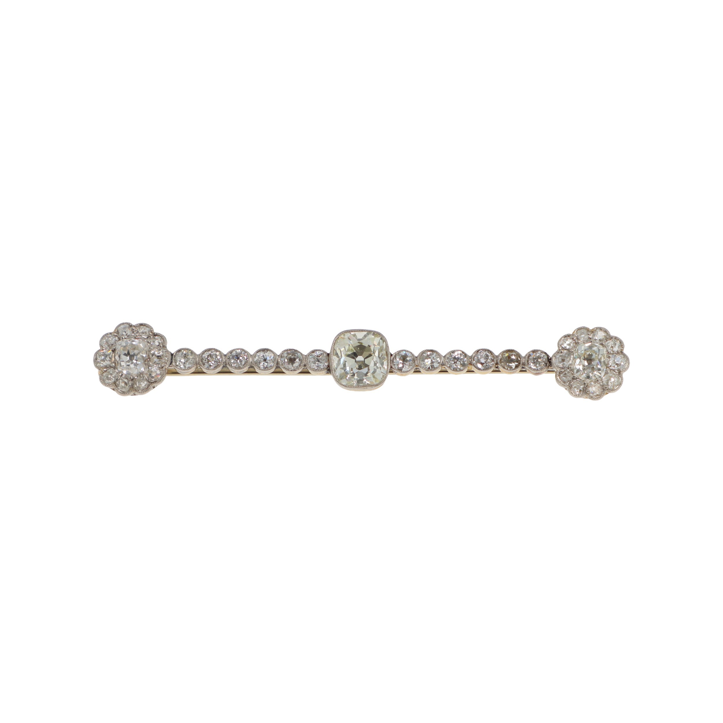 Expertise bijoux - Broche en or jaune et or gris 18k (750 millièmes) et platine (950 millièmes) centrée d'un diamant coussin taille ancienne d'environ 2,20 carats, épaulé de petits diamants et deux motifs de marguerite aux extrémités. Poids brut : 7,6 g. Long.: 7,4 cm Transformation - remontage - restaurations. Petit choc sur diamant principal - Adjugé 7 500 €