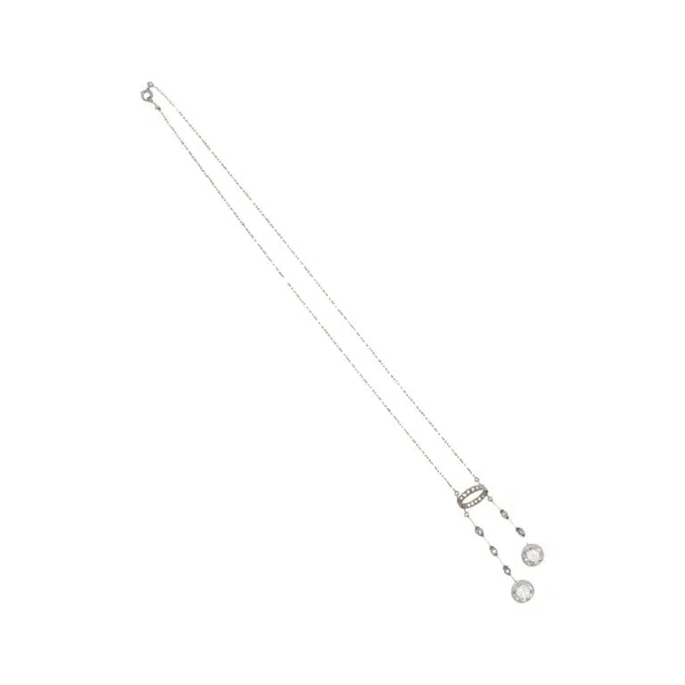 Expertise bijoux - Collier négligé en platine (950 millièmes) et or gris 18k (750 millièmes) serti de deux diamants taille ancienne d'environ 1,80 carat environ chacun, retenus par deux lignes de diamants et d'un motif en ellipse. Travail français vers 1910. Poids brut : 7,3 g. Long. chaîne : 40 cm