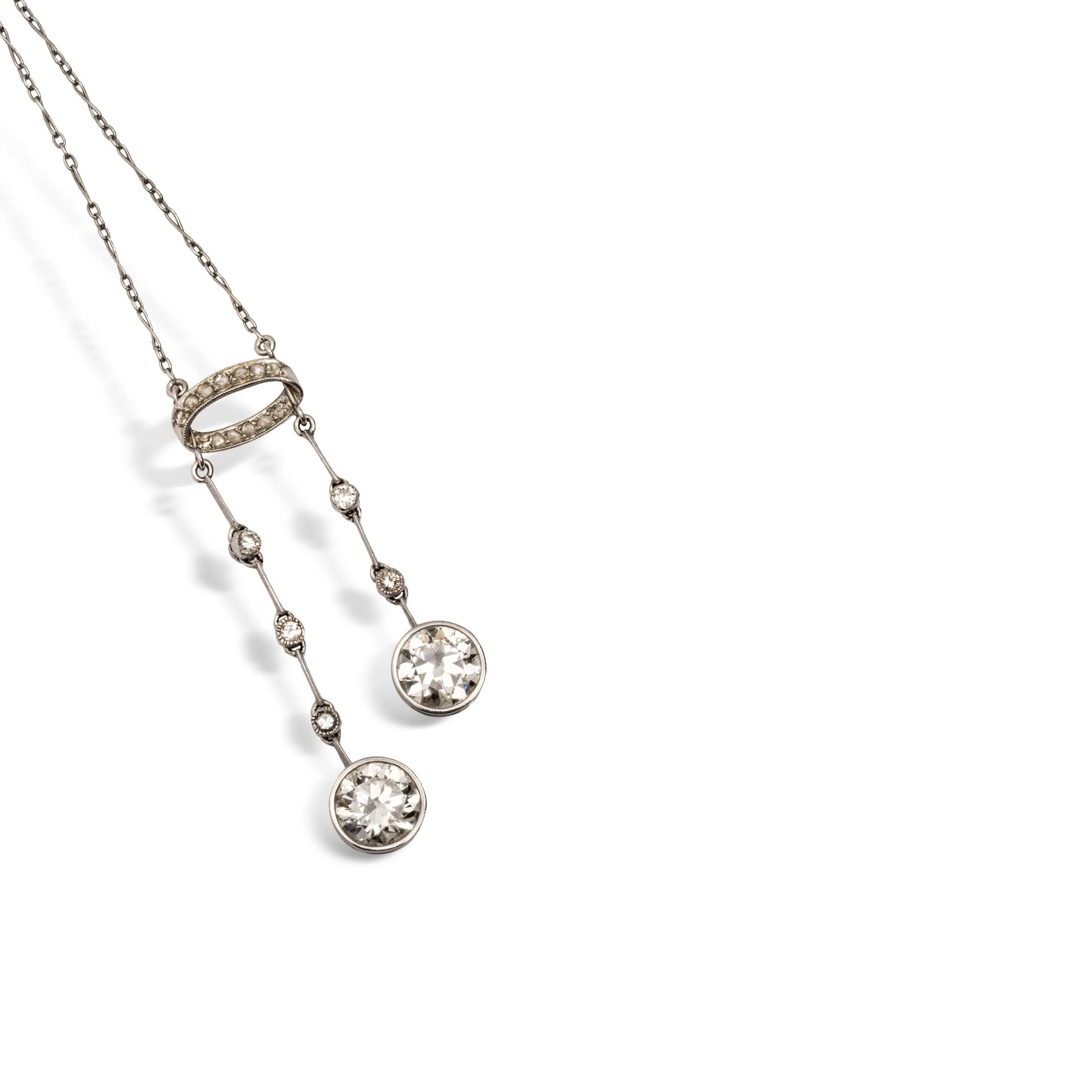 Expertise bijoux - Collier négligé en platine (950 millièmes) et or gris 18k (750 millièmes) serti de deux diamants taille ancienne d'environ 1,80 carat environ chacun, retenus par deux lignes de diamants et d'un motif en ellipse. Travail français vers 1910. Poids brut : 7,3 g. Long. chaîne : 40 cm
