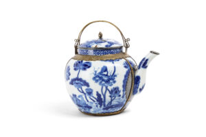 VIETNAM, fin du XVIIIe siècle - Théière en porcelaine "Bleu de Hué" - Le corps globulaire surmonté d'un col court, flanqué d'un bec verseur en "S" et accompagné d'un couvercle légèrement bombé. Présentant sur l'ensemble un fin décor en bleu de cobalt sur fond blanc d'un couple de canards évoluant parmi un étang de lotus, une frise de motifs losangiques ornant le col, le couvercle à décor d'un dragon à cinq griffes dans les nuées. Une marque "内府待東" (Nội phủ thị đông» soit « Palais intérieur enceinte de l'Est » ) à quatre caractères sous la base. Avec sa monture en laiton ciselé.