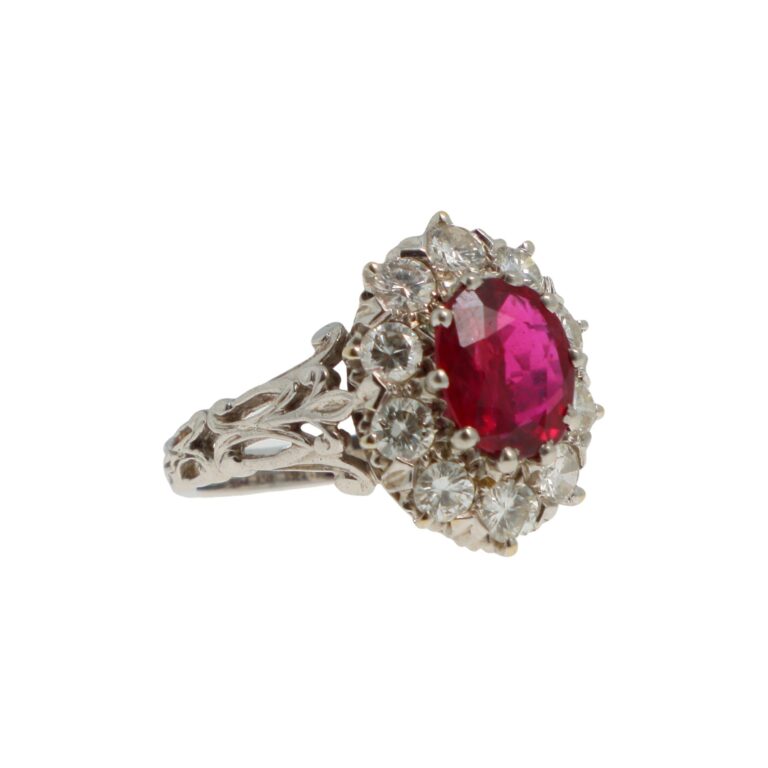Q0342_0001 - Bague marguerite en or gris 18K (750°/°°) et platine (950°/°°) centrée d'un rubis ovale de 1.67 ct entouré de diamants ronds taille brillant. Travail français. Poids brut: 5,6 gr. TD: 51 Rapport d'analyse de Bellerophon février 2026, précisant son origine de Thaïlande et l'absence de modifications thermiques. - Adjugé 4 300 €