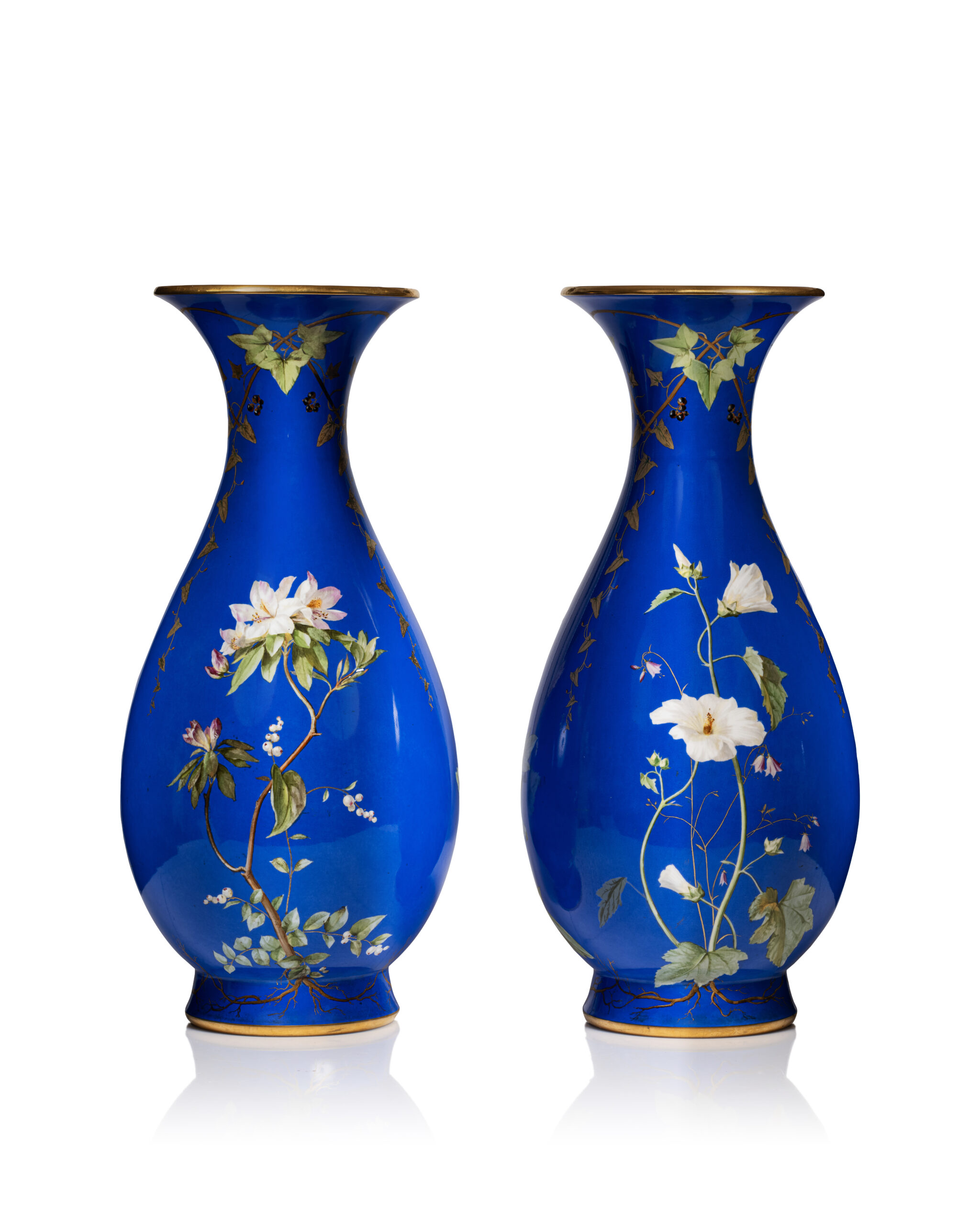 Sèvres - Description : Paire de vases balustres dits “Bertin” de 2e grandeur en porcelaine dure, à fond bleu et décor naturaliste polychrome de fleurs, blanches sur une face et rouges de l’autre, alternées de frises de feuilles de lierre enlacées, large filet or sur les bords. Bon état, avec leurs doublures internes en tôle. Manufacture impériale de Sèvres, 1853. Marques au tampon vert “S. 52” de fabrication pour 1852, et marque au tampon rouge de décor à l’aigle impériale datée “S. 53” pour 1853. H. 53,5 x D. 19 cm. Adjugé 4 200 €