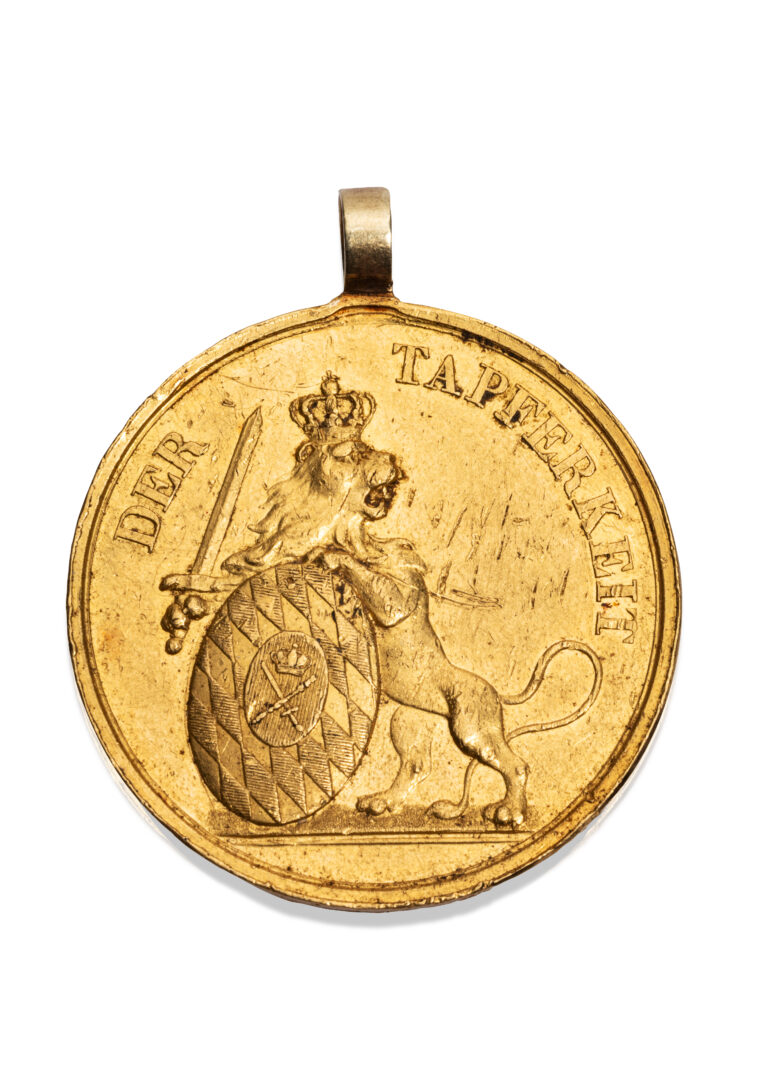 BAVIÈRE, Médaille “Pour le Courage” (Der Tapferkeit), en or (916 millièmes), l’avers au profil gauche du roi Maximilien-Joseph Ier de Bavière (1799-1825), le revers à décor allégorique du lion de Bavière couronné, dressé, armé et soutenant les armes du Royaume de Bavière. Avec bélière en or (585 millièmes), anciennement rapportée. Petites rayures et enfoncement en bordure. Bavière, début du XIXe siècle, 1806-1825. D. 3,5 cm. Poids brut : 21,0 g. Adjugé 5 000 €
