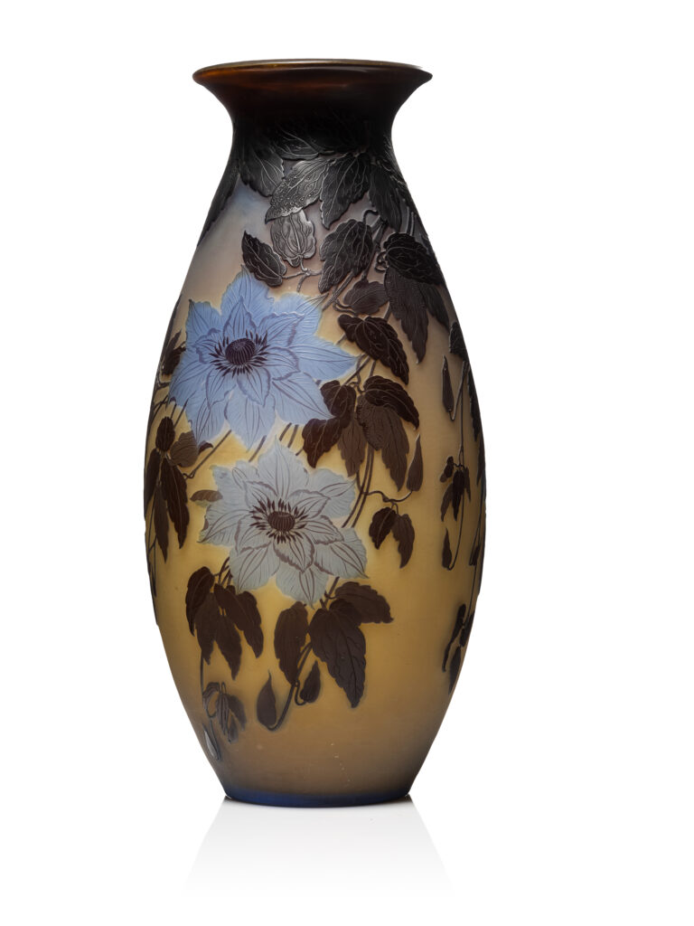 GALLE- Nancy - "Clématite Joséphine" - Description : Important vase en verre double de forme balustre méplate à large pied circulaire débordant et court col ourlé. Décor tombant gravé en réserve de feuilles et de fleurs de couleur bleu-violet et brunes sur un fond jaune-orangé. Signé "Gallé" en réserve, dans le décor. H : 58,5 cm - Adjugé 6 500 €
