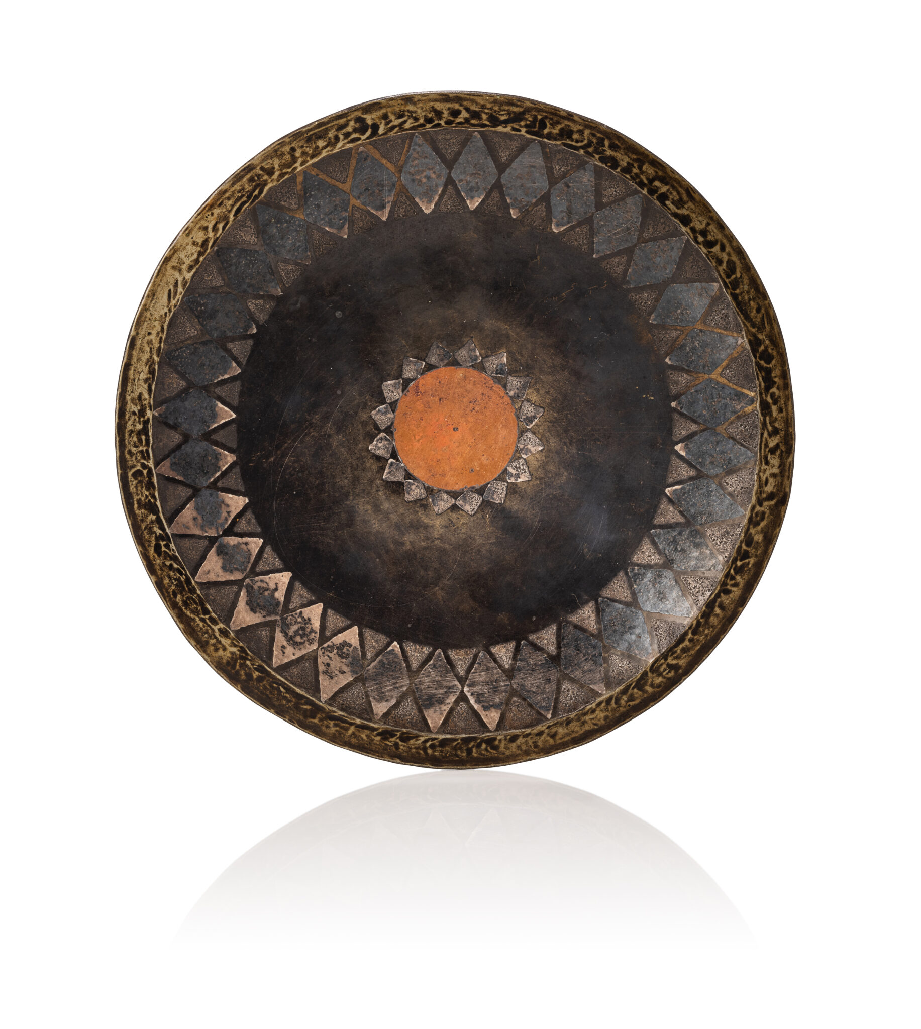 Claudius LINOSSIER (1893 - 1953) Description : 1927 Assiette circulaire en dinanderie de cuivre patiné noire. Décor d'une frise de losanges argenté et d'un disque centrale ocre. Signée et datée au dos "Cl.Linossier 6 mai 1927". D : 19 cm A black patinated copperware plate with a silver and ocher geometrical decor made by Claudius Linossier on May, 1927 the 6th. Signed "Cl.Linossier 6 mai 1927" on the back - Adjugé 2 000 €