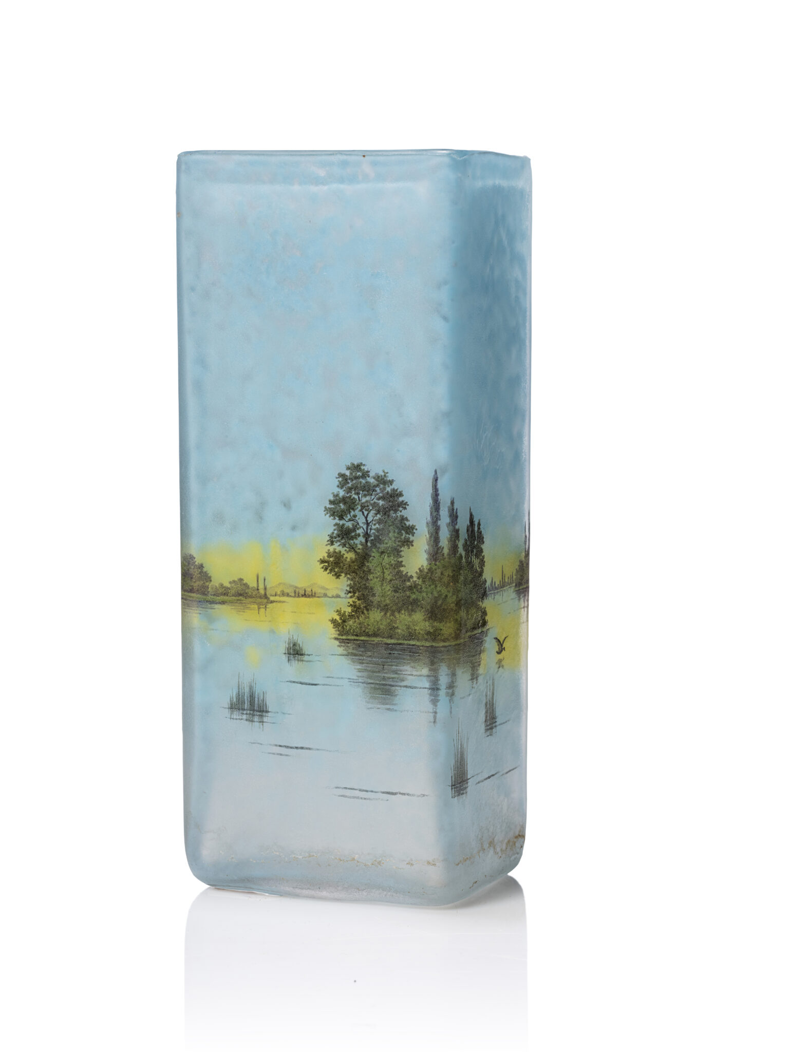 DAUM - Nancy Description : Vase à corps quadrangulaire en verre teinté bleu et jaune à décor peint en grisaille d'un paysage lacustre. Signé sous la base "Daum # Nancy". H : 18 cm - Adjugé 1 500 €