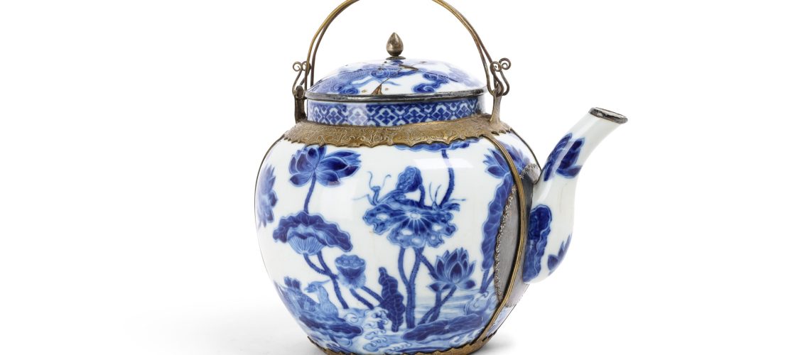VIETNAM, fin du XVIIIe siècle - Théière en porcelaine "Bleu de Hué" - Le corps globulaire surmonté d'un col court, flanqué d'un bec verseur en "S" et accompagné d'un couvercle légèrement bombé. Présentant sur l'ensemble un fin décor en bleu de cobalt sur fond blanc d'un couple de canards évoluant parmi un étang de lotus, une frise de motifs losangiques ornant le col, le couvercle à décor d'un dragon à cinq griffes dans les nuées. Une marque "内府待東" (Nội phủ thị đông» soit « Palais intérieur enceinte de l'Est » ) à quatre caractères sous la base. Avec sa monture en laiton ciselé.